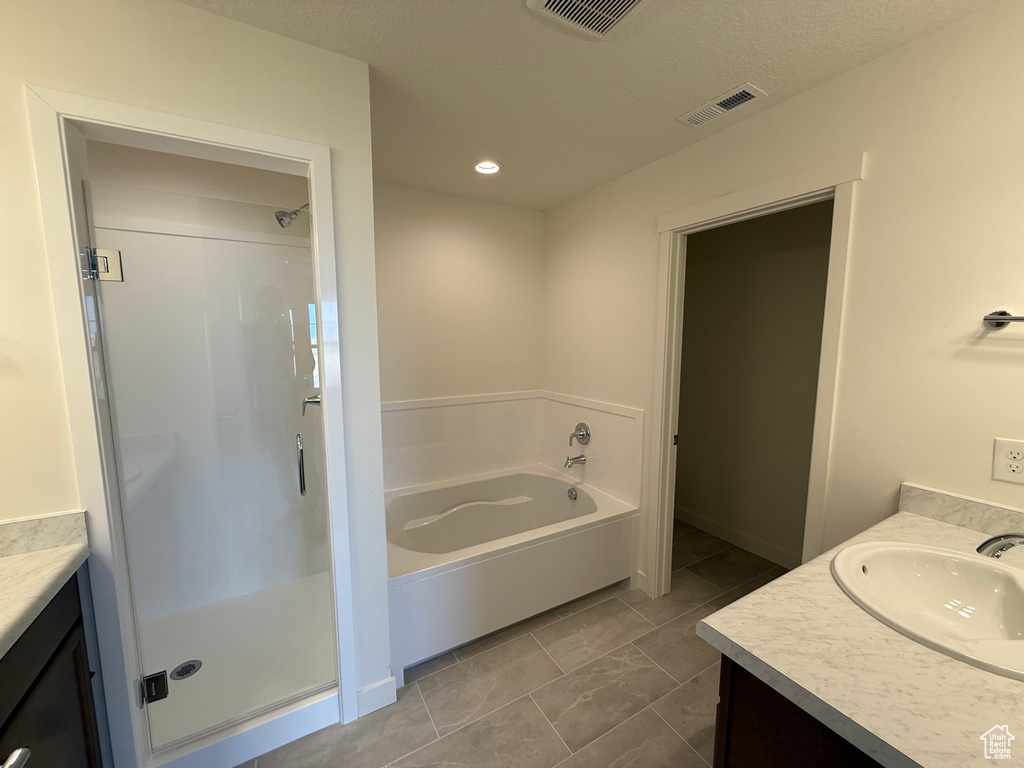 Bathroom featuring vanity, a shower stall, a garden tub, and recessed lighting