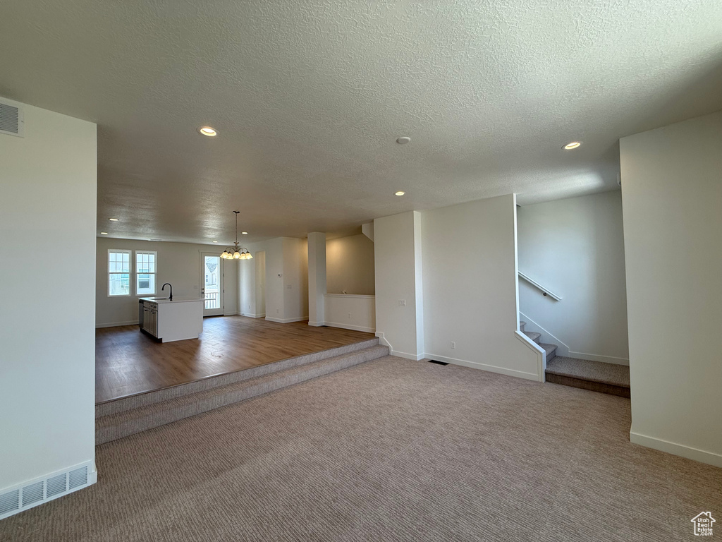 Unfurnished room featuring carpet floors, recessed lighting, a chandelier, stairs, and a textured ceiling