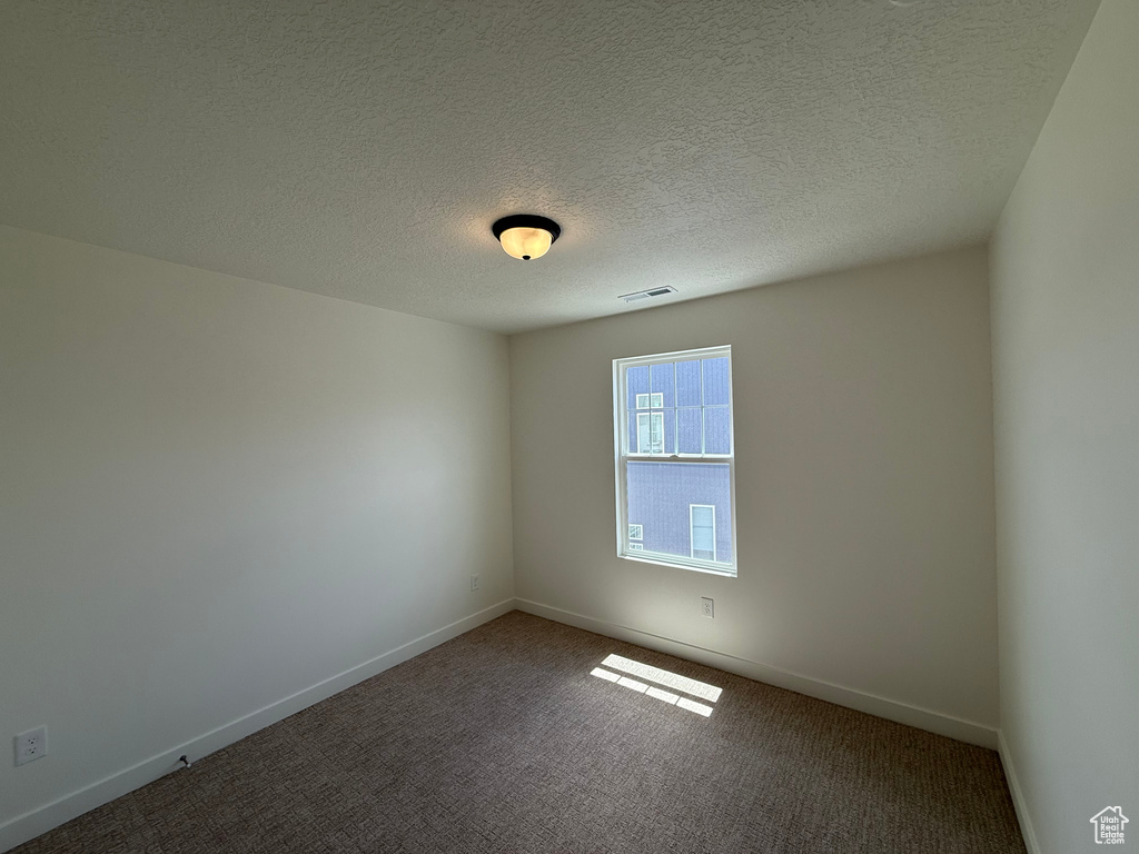 Carpeted empty room featuring baseboards and a textured ceiling