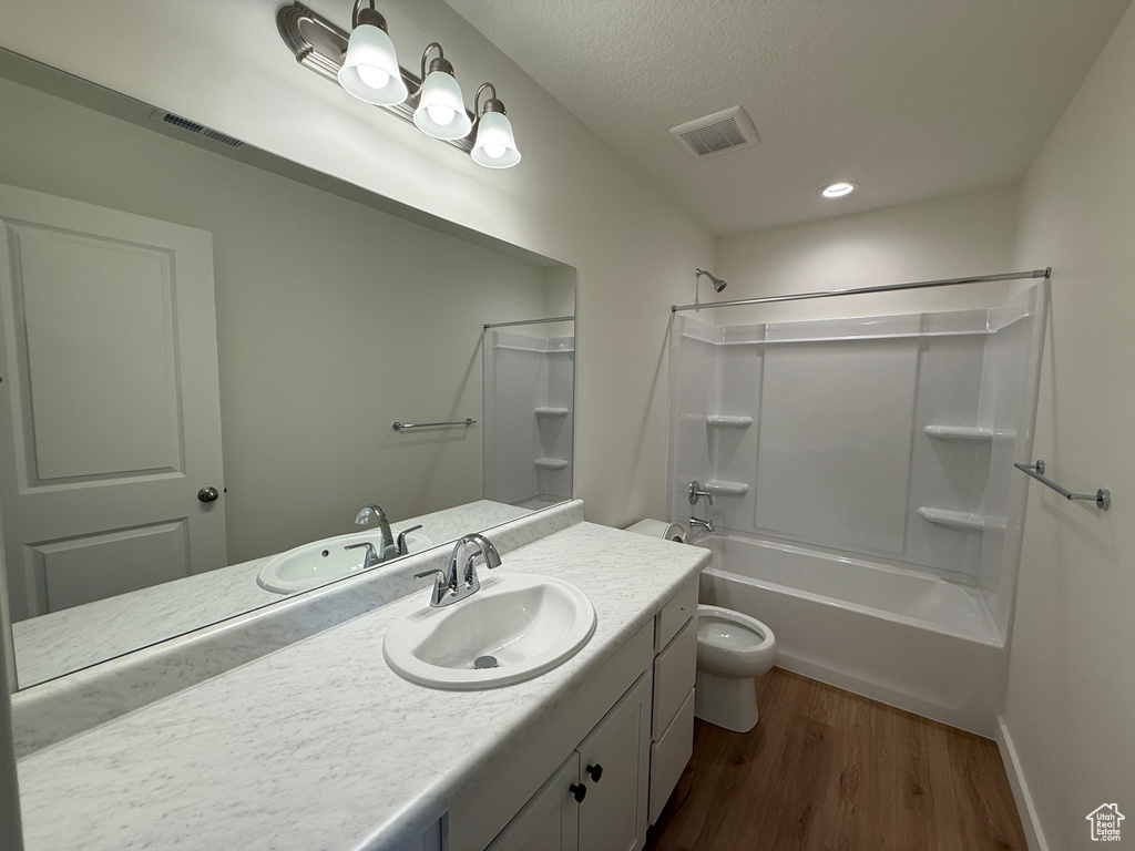 Bathroom with vanity, wood finished floors, tub / shower combination, and a textured ceiling
