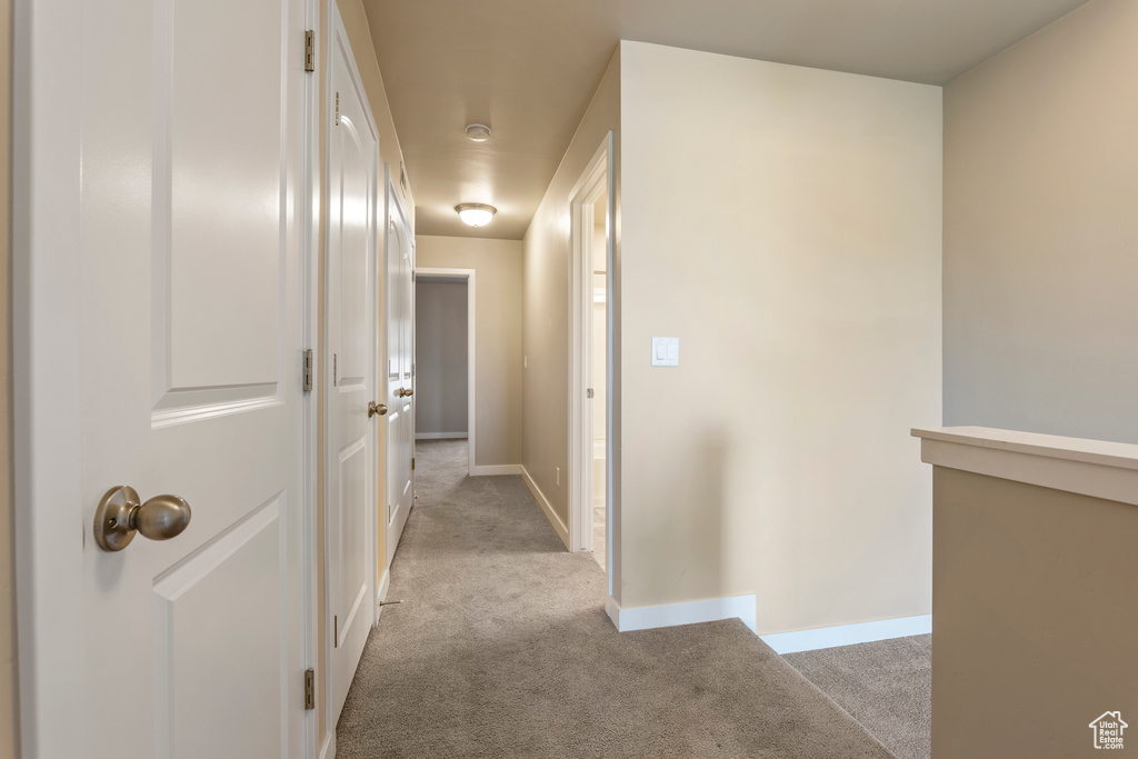 Hallway featuring light carpet and baseboards