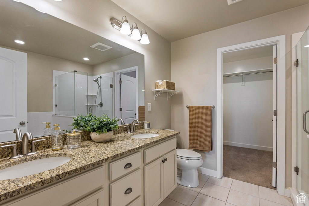 Bathroom with a shower stall, tile patterned floors, double vanity, and a walk in closet