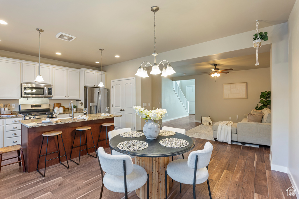 Dining area with dark wood-type flooring, stairway, recessed lighting, and ceiling fan