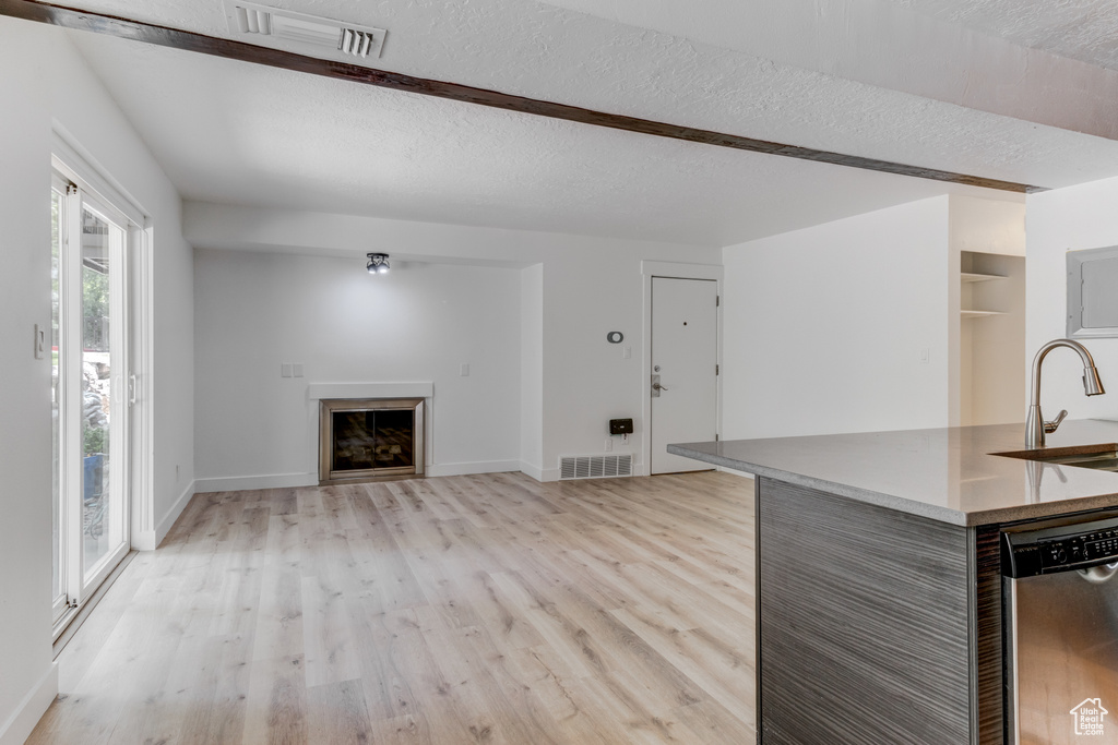 Unfurnished living room with light wood-type flooring, a fireplace, and a textured ceiling
