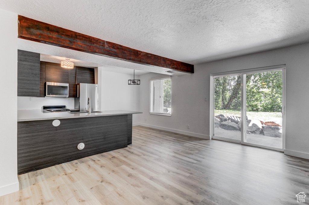 Kitchen with appliances with stainless steel finishes, modern cabinets, light countertops, light wood-style flooring, and a textured ceiling