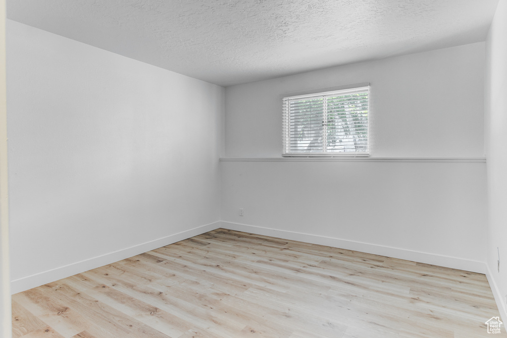 Unfurnished room with wood finished floors and a textured ceiling