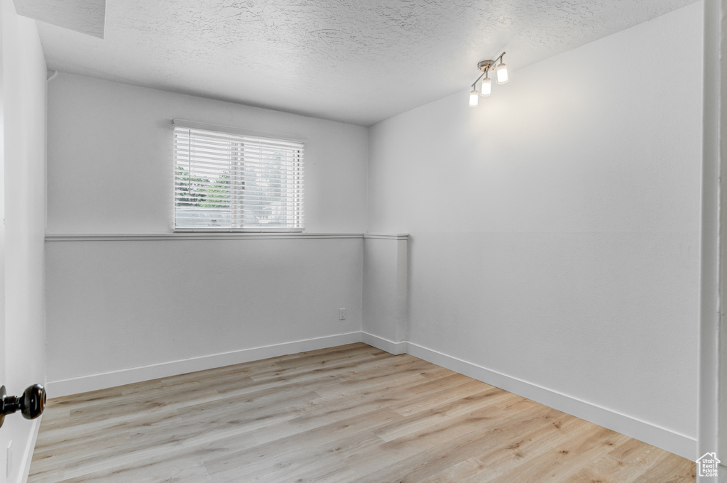 Empty room featuring a textured ceiling and wood finished floors