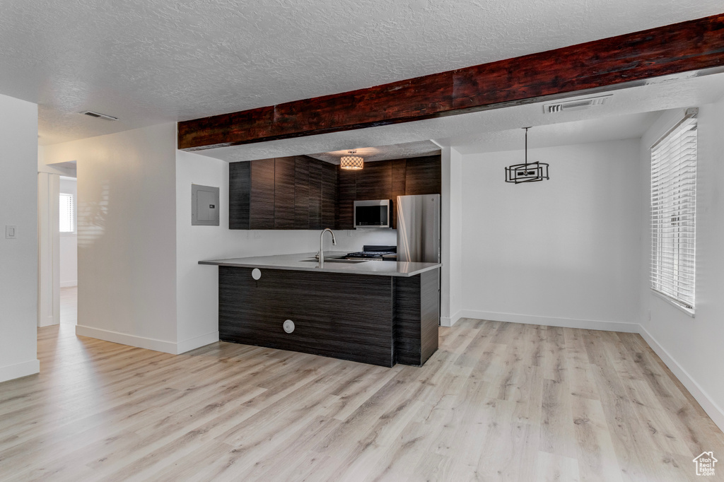 Kitchen with stainless steel appliances, a peninsula, modern cabinets, light countertops, and light wood-style flooring
