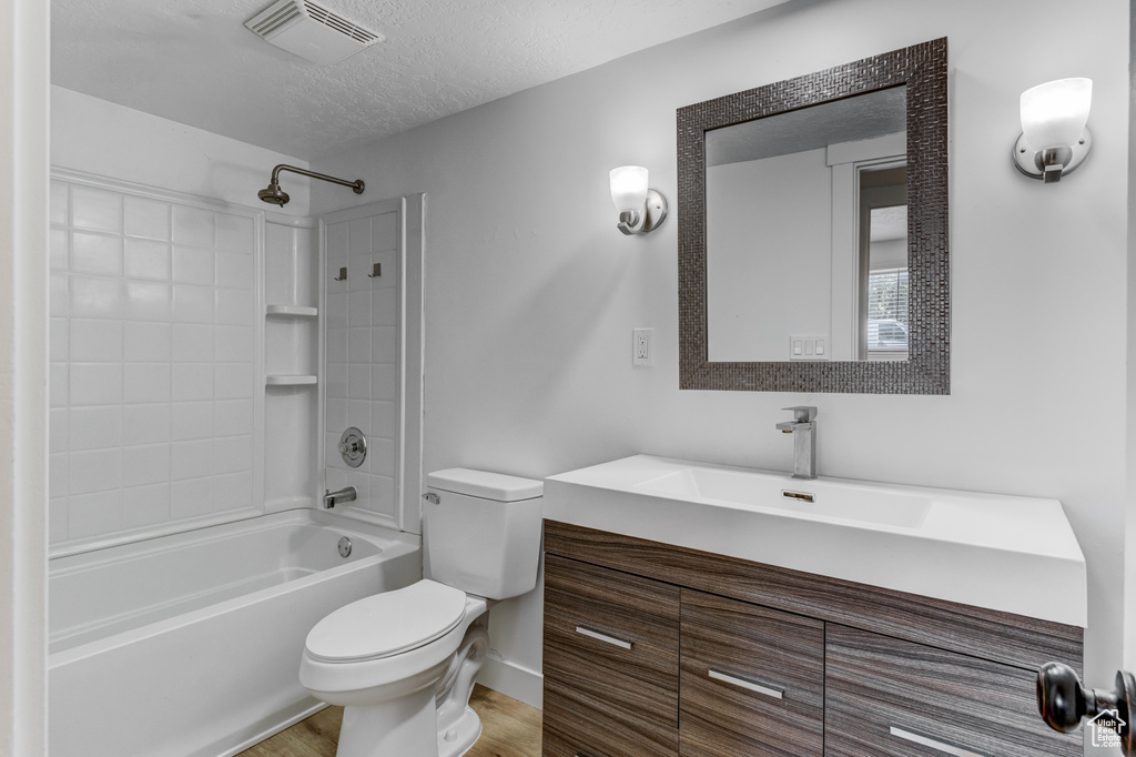 Full bathroom featuring bathtub / shower combination, vanity, a textured ceiling, and wood finished floors