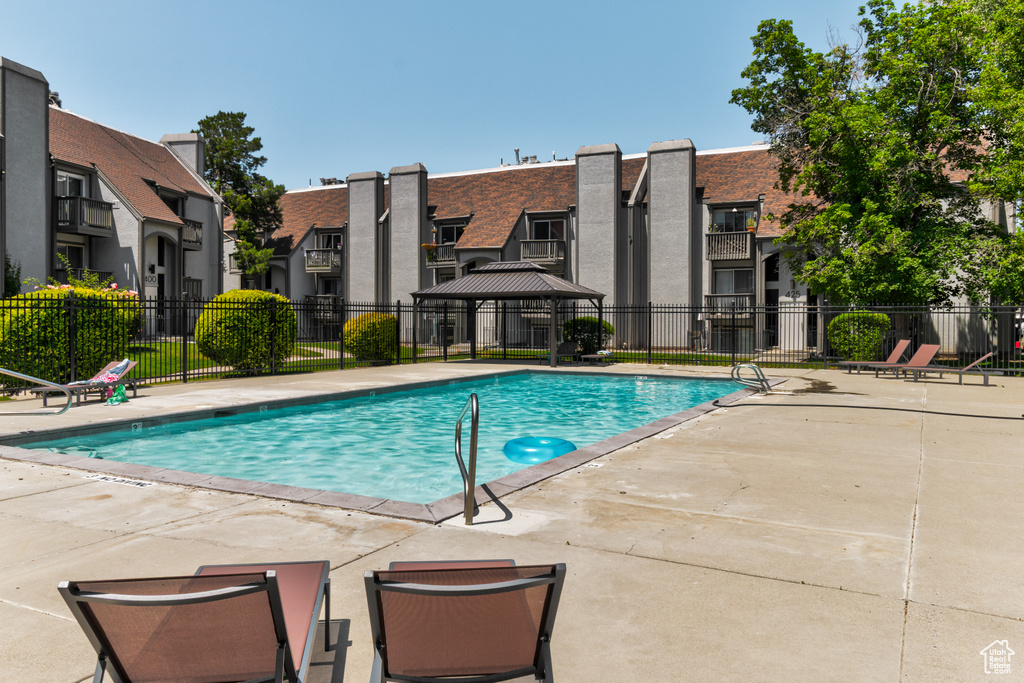 Community pool with a patio area, a gazebo, and a residential view
