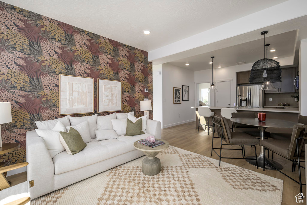 Living room with wood finished floors, recessed lighting, wallpapered walls, and an accent wall