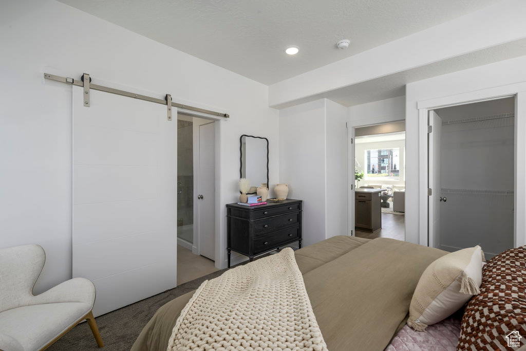 Bedroom with a barn door, carpet, and recessed lighting