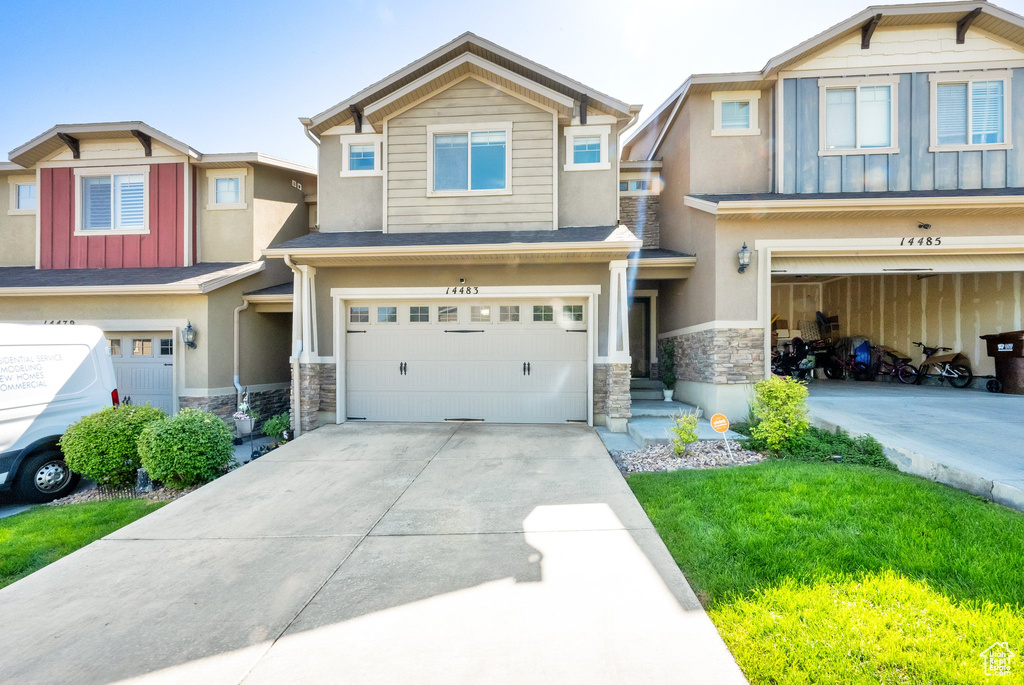 View of front of home featuring stone siding, a garage, driveway, and stucco siding