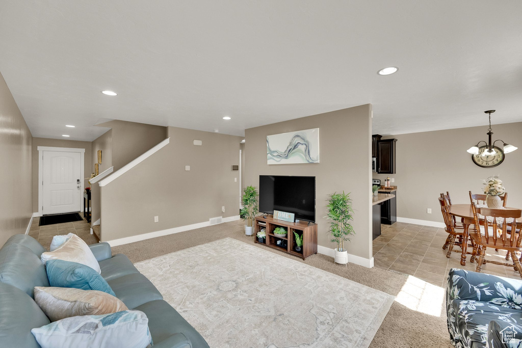 Living area with a chandelier, light carpet, recessed lighting, and stairway