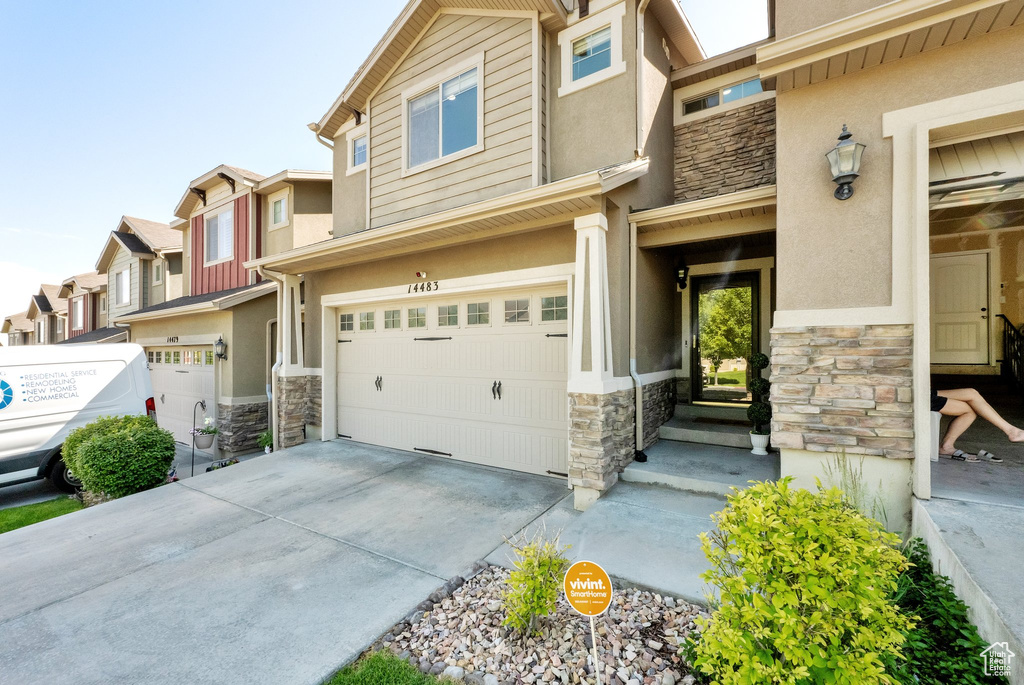 Multi unit property with stone siding, stucco siding, and a garage