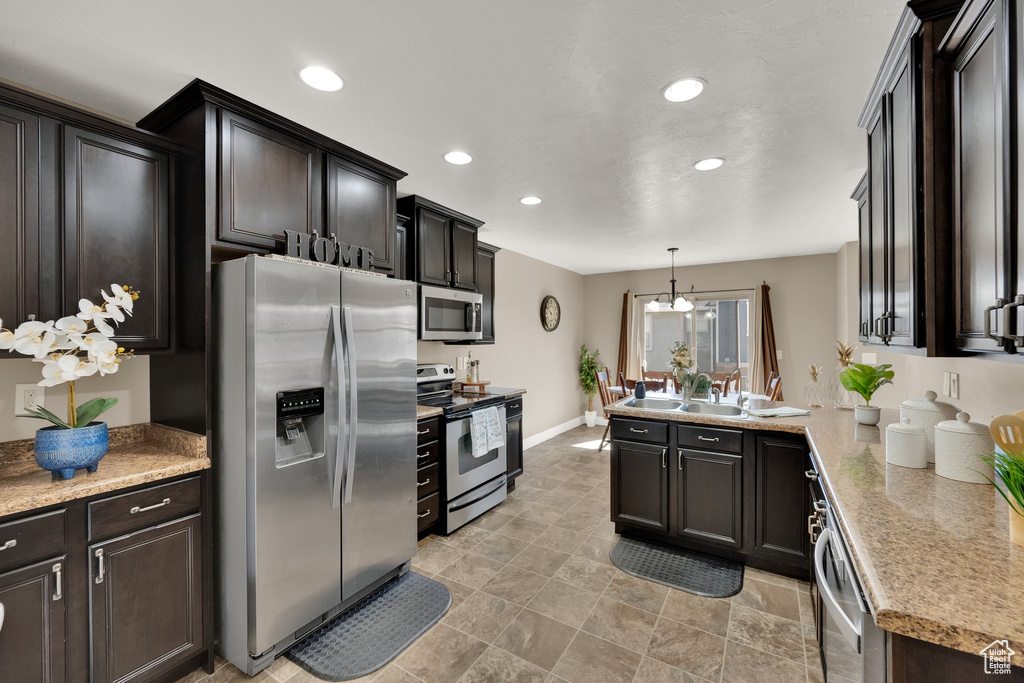 Kitchen featuring stainless steel appliances, recessed lighting, a peninsula, light countertops, and pendant lighting