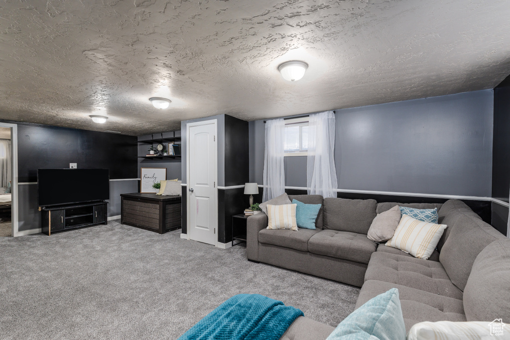 Carpeted living room featuring a textured ceiling and baseboards
