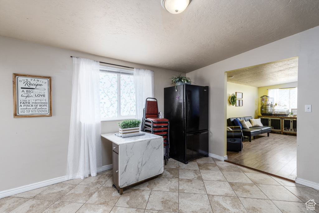Kitchen with freestanding refrigerator, healthy amount of natural light, a textured ceiling, and light countertops
