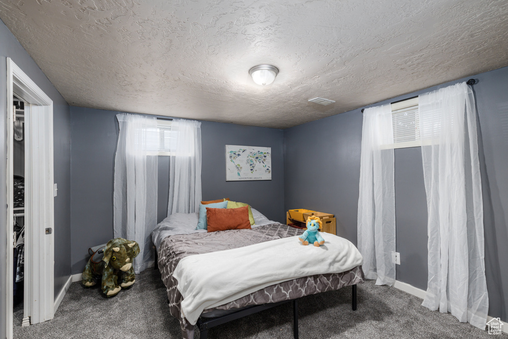 Carpeted bedroom with a textured ceiling and baseboards
