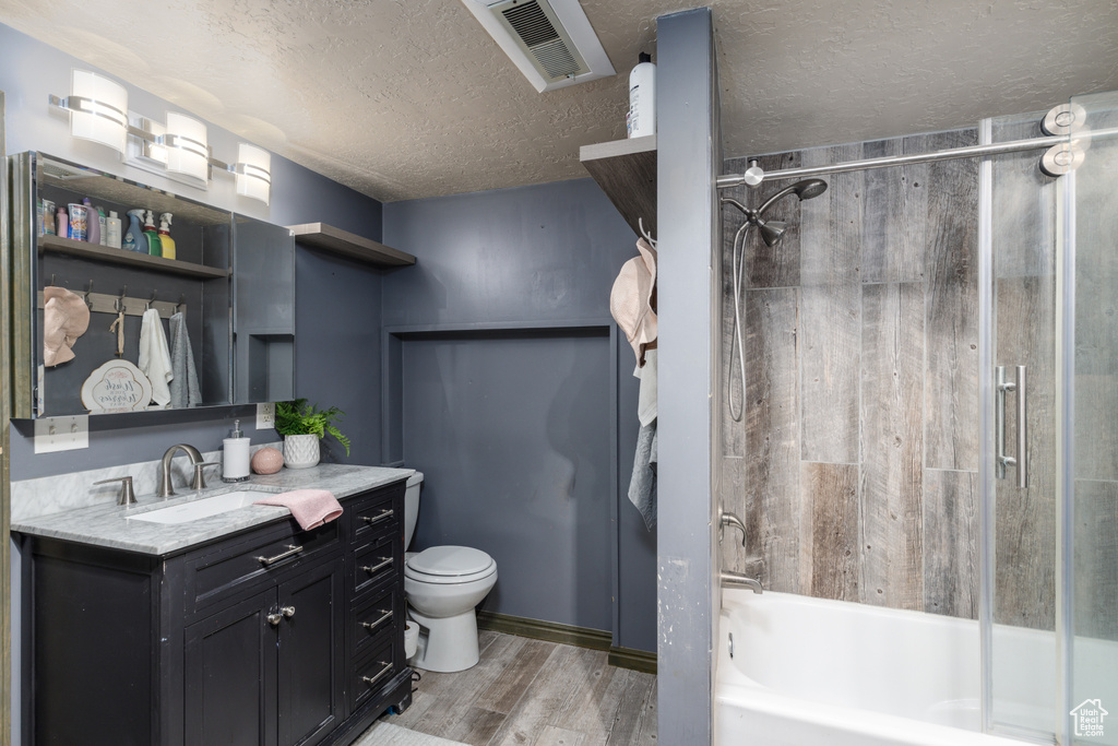 Bathroom with wood finished floors, vanity, bathtub / shower combination, and a textured ceiling