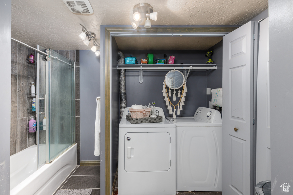 Washroom featuring independent washer and dryer, a textured ceiling, and tile patterned flooring