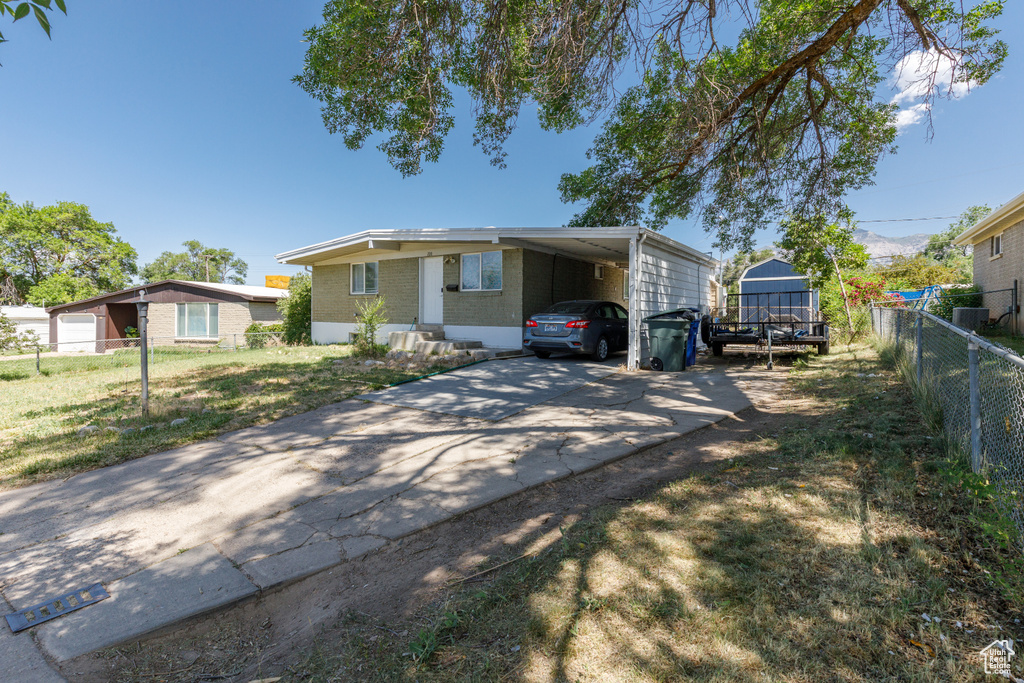 View of front of house featuring driveway, brick siding, and an attached carport