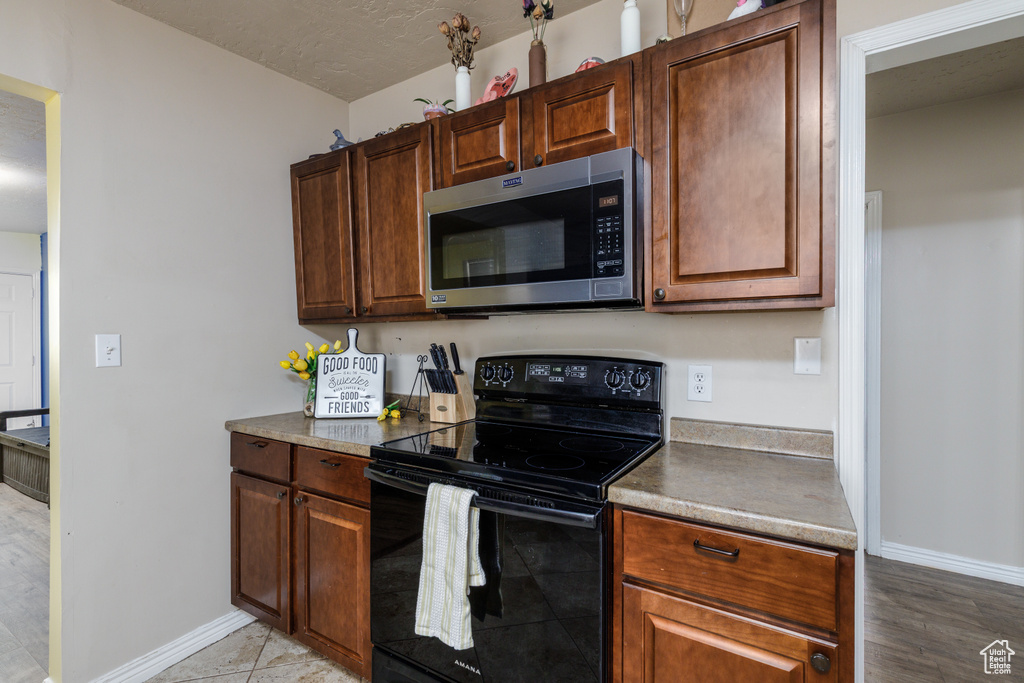 Kitchen featuring stainless steel microwave, black range with electric cooktop, and light wood finished floors