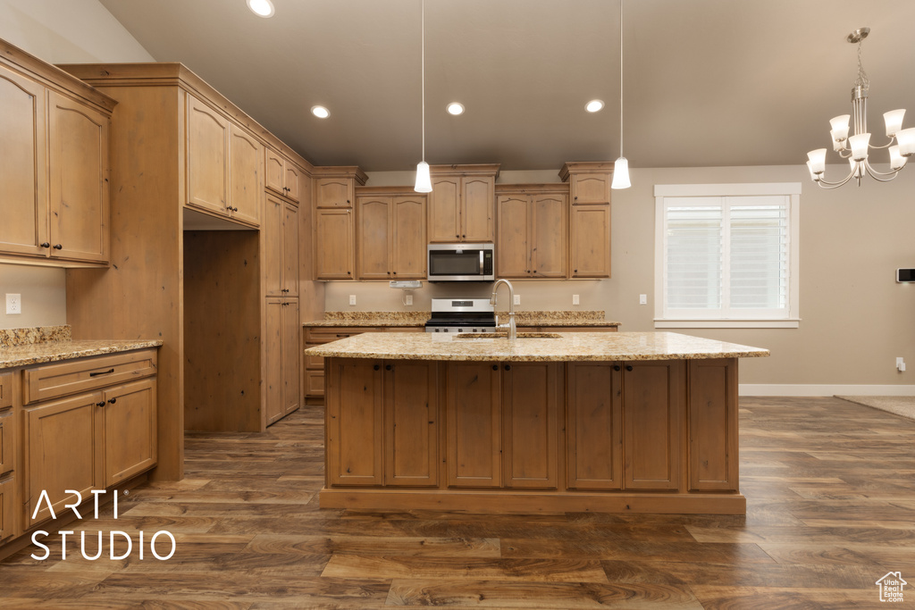 Kitchen featuring stainless steel appliances, recessed lighting, dark wood-type flooring, light stone countertops, and a center island with sink