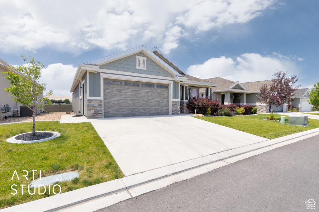 Craftsman-style home with an attached garage, a front yard, driveway, stone siding, and board and batten siding
