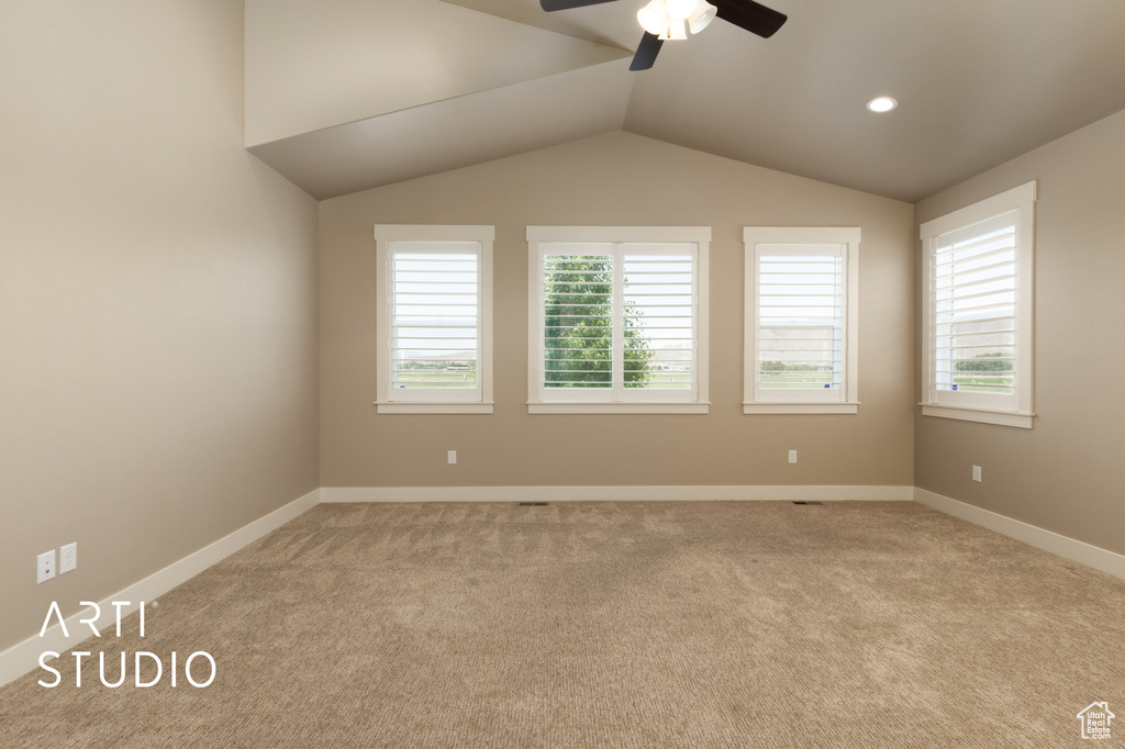Empty room with a ceiling fan, light carpet, and lofted ceiling