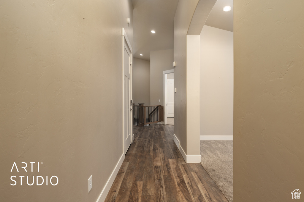 Hallway with dark wood-type flooring, an upstairs landing, recessed lighting, and arched walkways