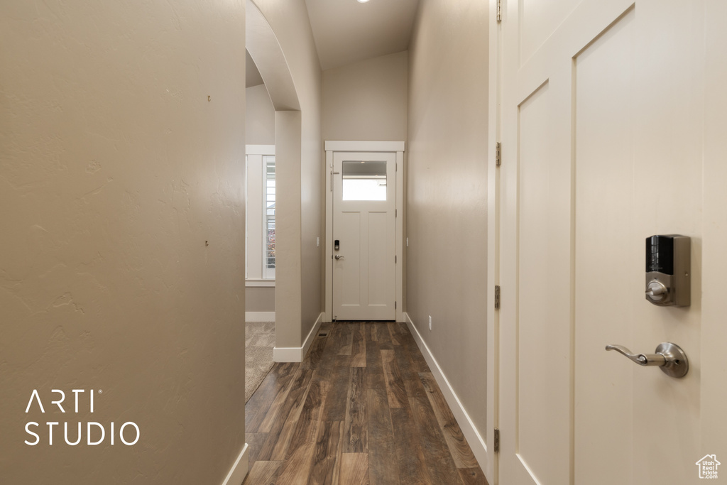 Doorway to outside featuring arched walkways and dark wood-type flooring