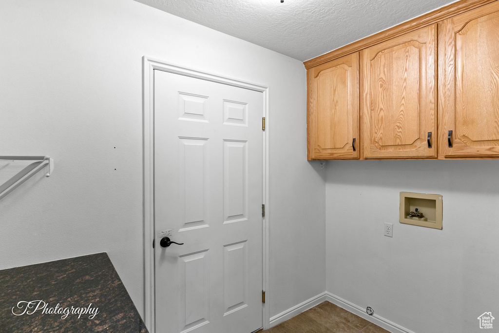 Washroom featuring cabinet space, hookup for a washing machine, and a textured ceiling