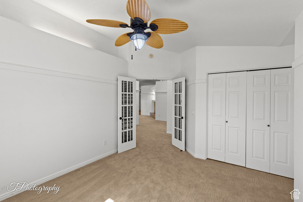 Unfurnished bedroom featuring carpet flooring, vaulted ceiling, a heating unit, a closet, and ceiling fan
