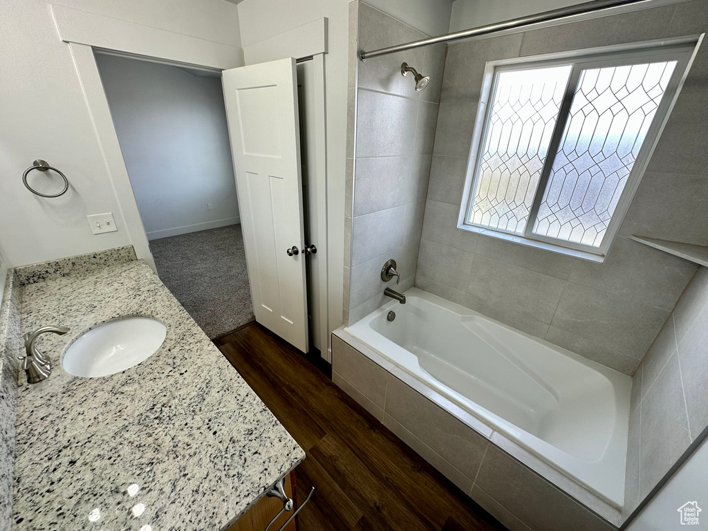 Bathroom featuring wood finished floors, vanity, and tiled shower / bath combo