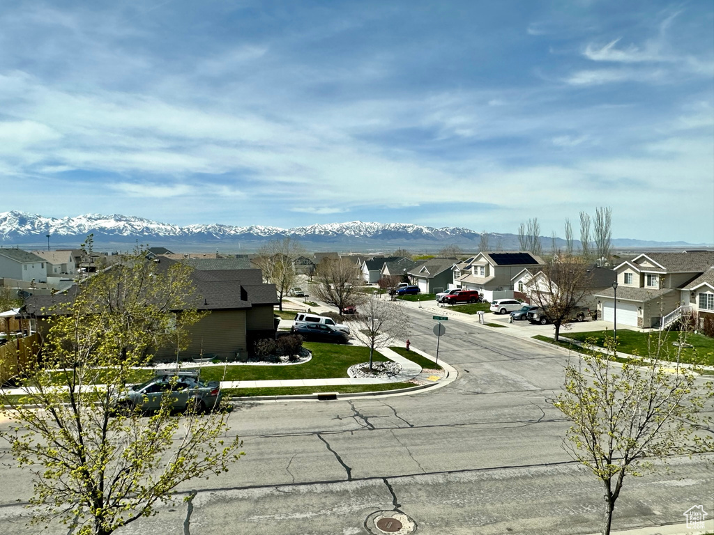View of asphalt street with a residential view, a mountain view, and curbs