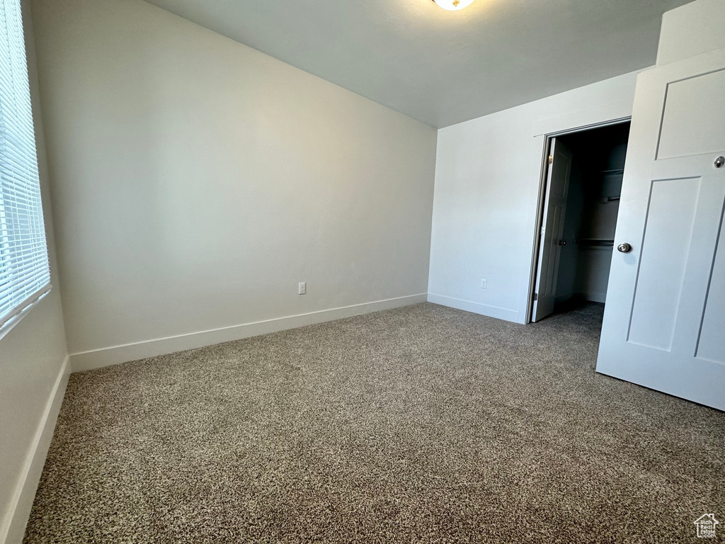 Unfurnished bedroom featuring carpet floors, a spacious closet, and a closet