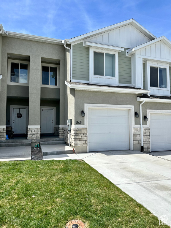 View of property with a garage, stone siding, stucco siding, and concrete driveway