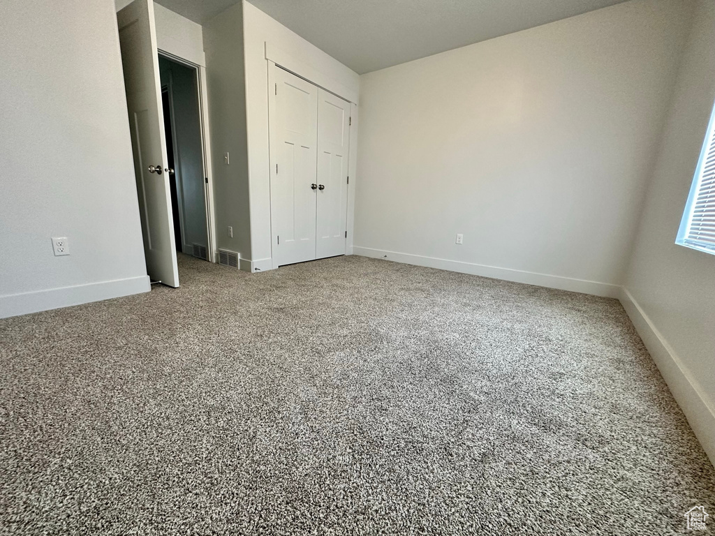 Unfurnished bedroom with carpet and a closet