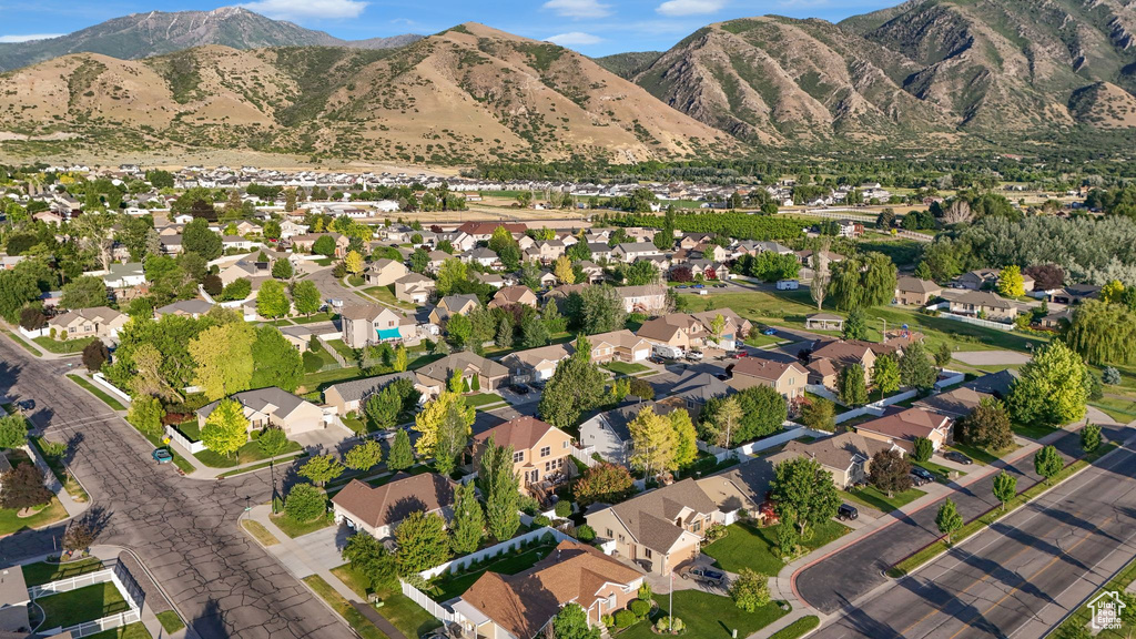 Aerial view of property and surrounding area featuring a mountainous background and nearby suburban area