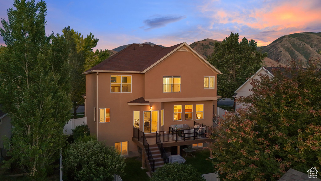 Back of house at dusk featuring stucco siding, stairs, and a deck with mountain view