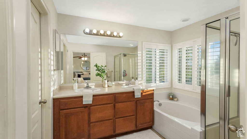 Bathroom featuring double vanity, a stall shower, a garden tub, and ceiling fan