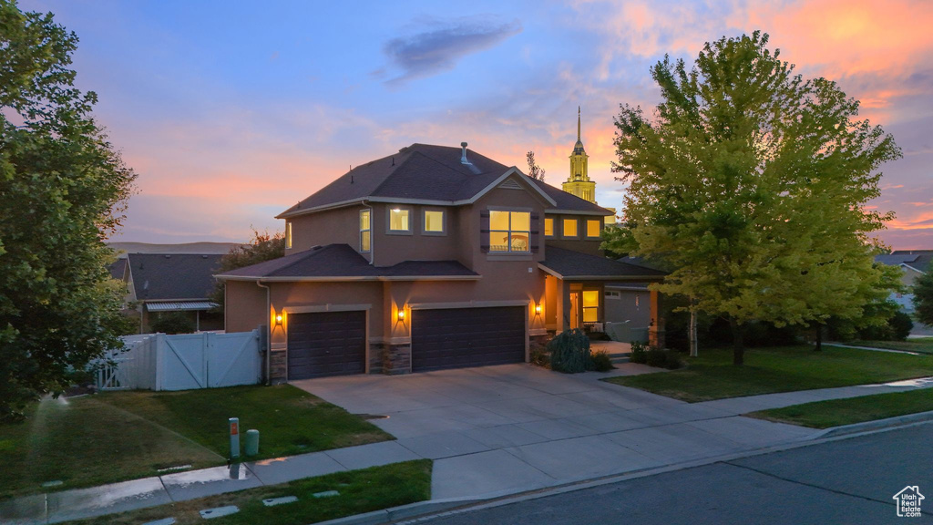 Traditional-style house with stucco siding, an attached garage, concrete driveway, a gate, and stone siding