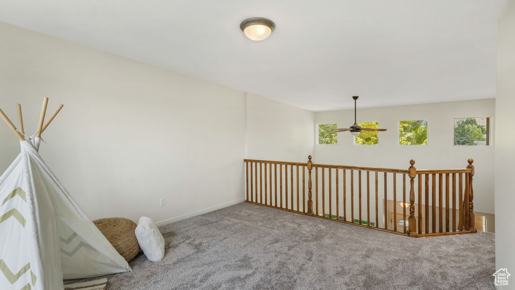 Carpeted empty room featuring a ceiling fan and baseboards