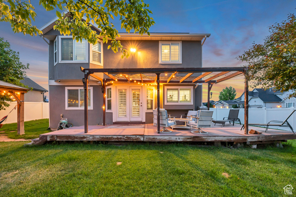 Back of house featuring stucco siding, a deck, and french doors