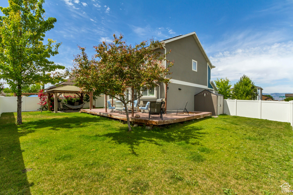 Back of house featuring a gazebo, a fenced backyard, a deck, and stucco siding