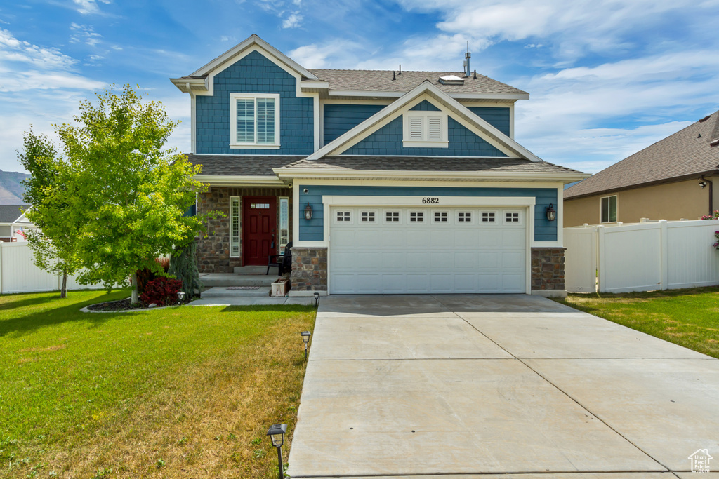 Craftsman-style home with stone siding, concrete driveway, and a shingled roof