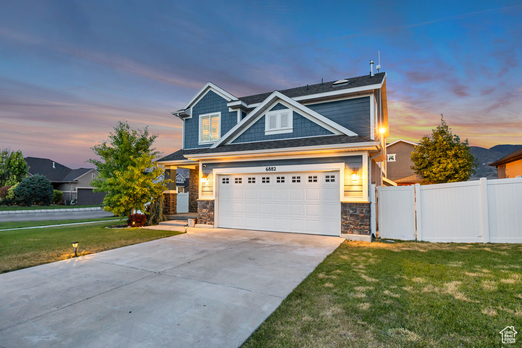 View of front of home featuring stone siding, driveway, and a garage