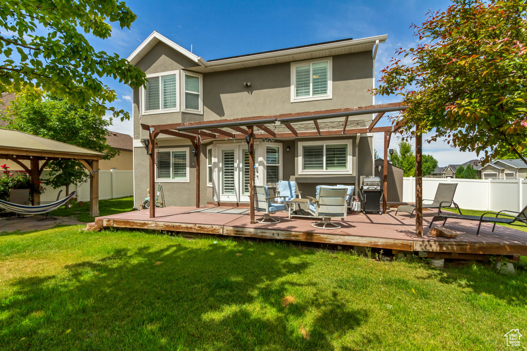 Rear view of property with stucco siding, a pergola, a fenced backyard, a gazebo, and a wooden deck