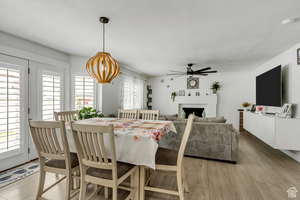Dining area with ceiling fan, light wood-style flooring, and a fireplace